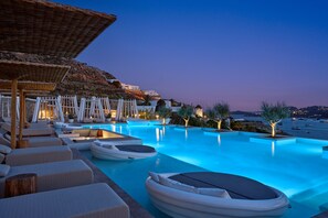 A poolside area with lounge chairs, umbrellas, and boats.