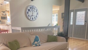 Un salón con un sofá color crema, una mesa de centro de madera y un gran reloj de pared.