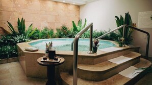 A spa area with a hot tub, steps, and a table with a drink and a tray. - Princess Mundo Imperial (Acapulco)