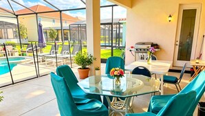 Un patio vitré avec une piscine, un espace salon extérieur et un coin barbecue.