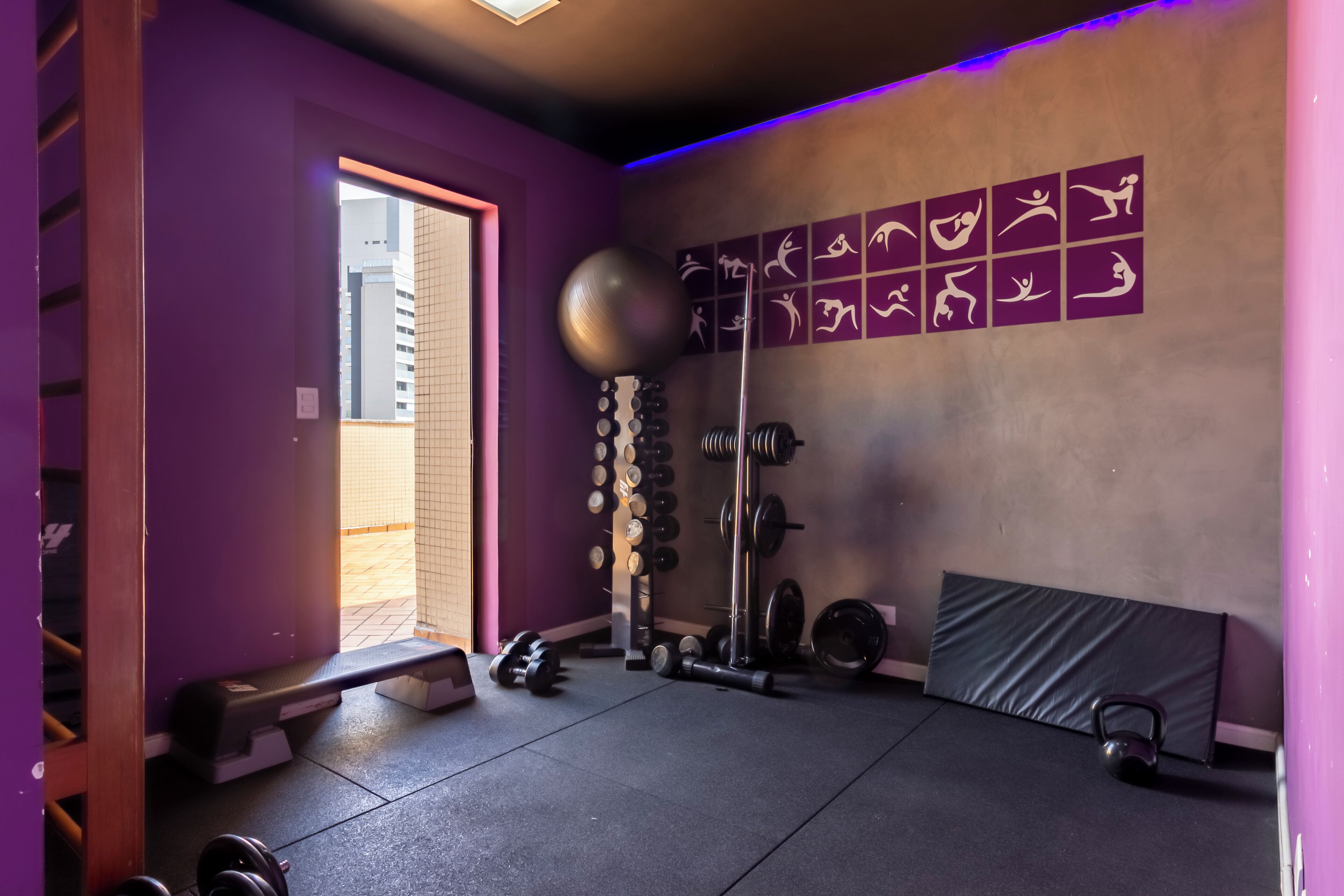 Un gimnasio con paredes moradas, varios pesas y equipo de ejercicio.