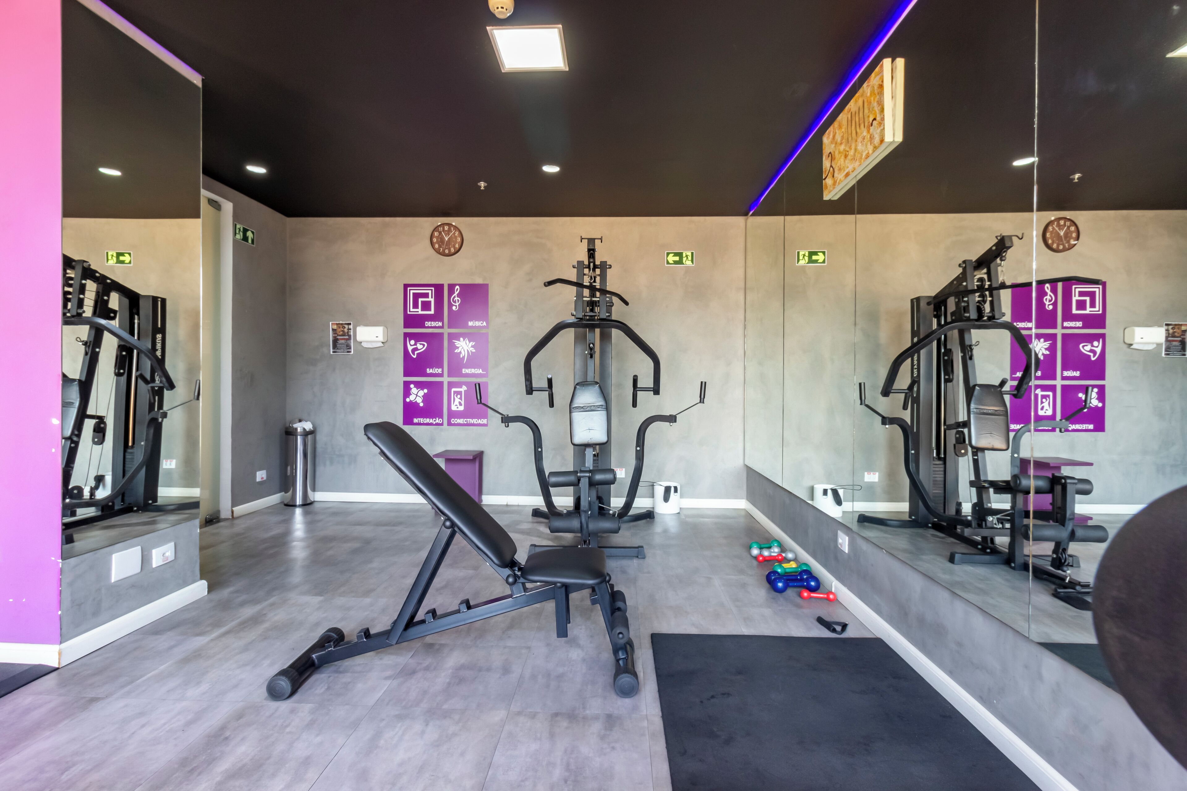 A modern gym with weightlifting equipment, mirrors, and exercise machines.