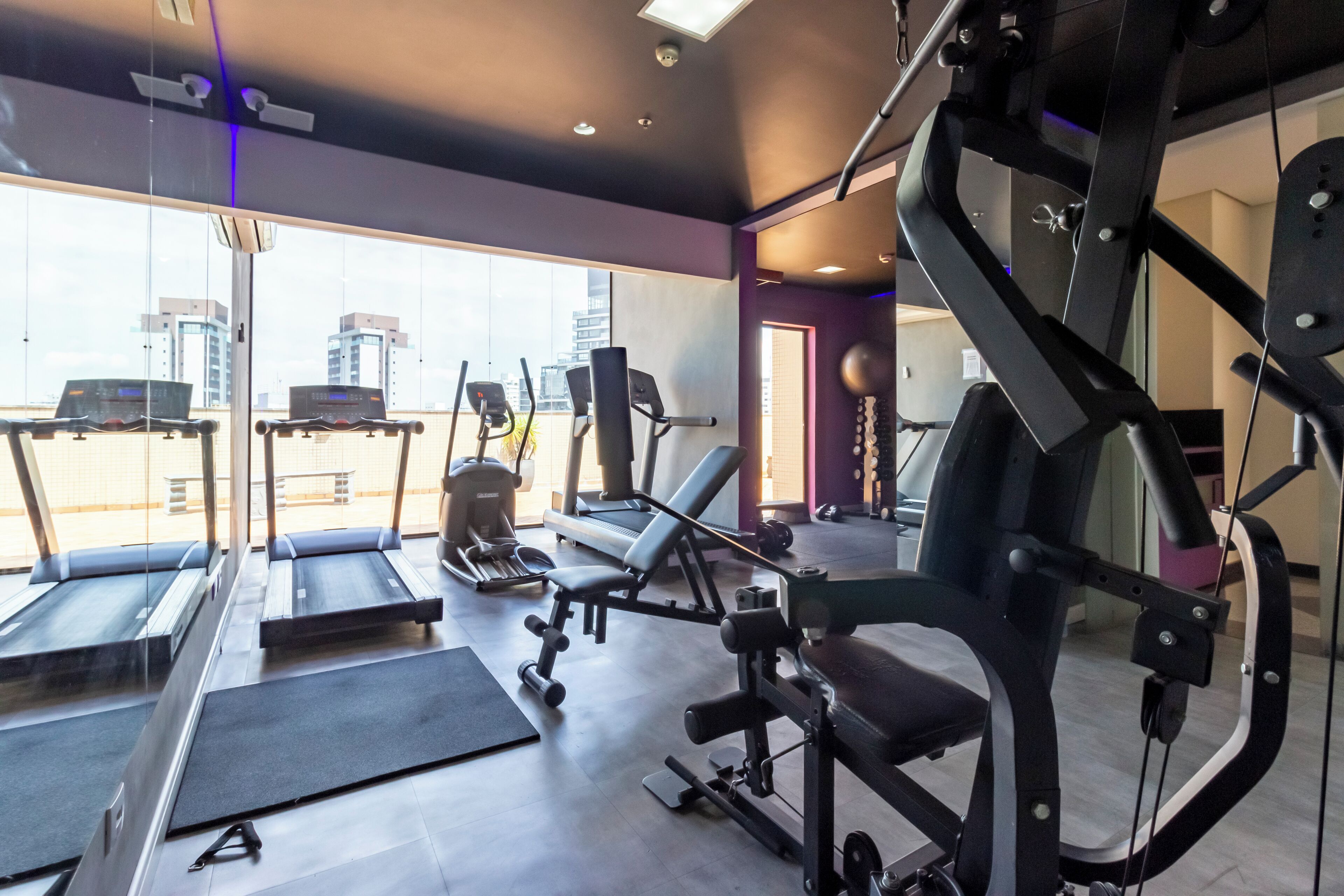 A gym with treadmills, weight machines, and benches.