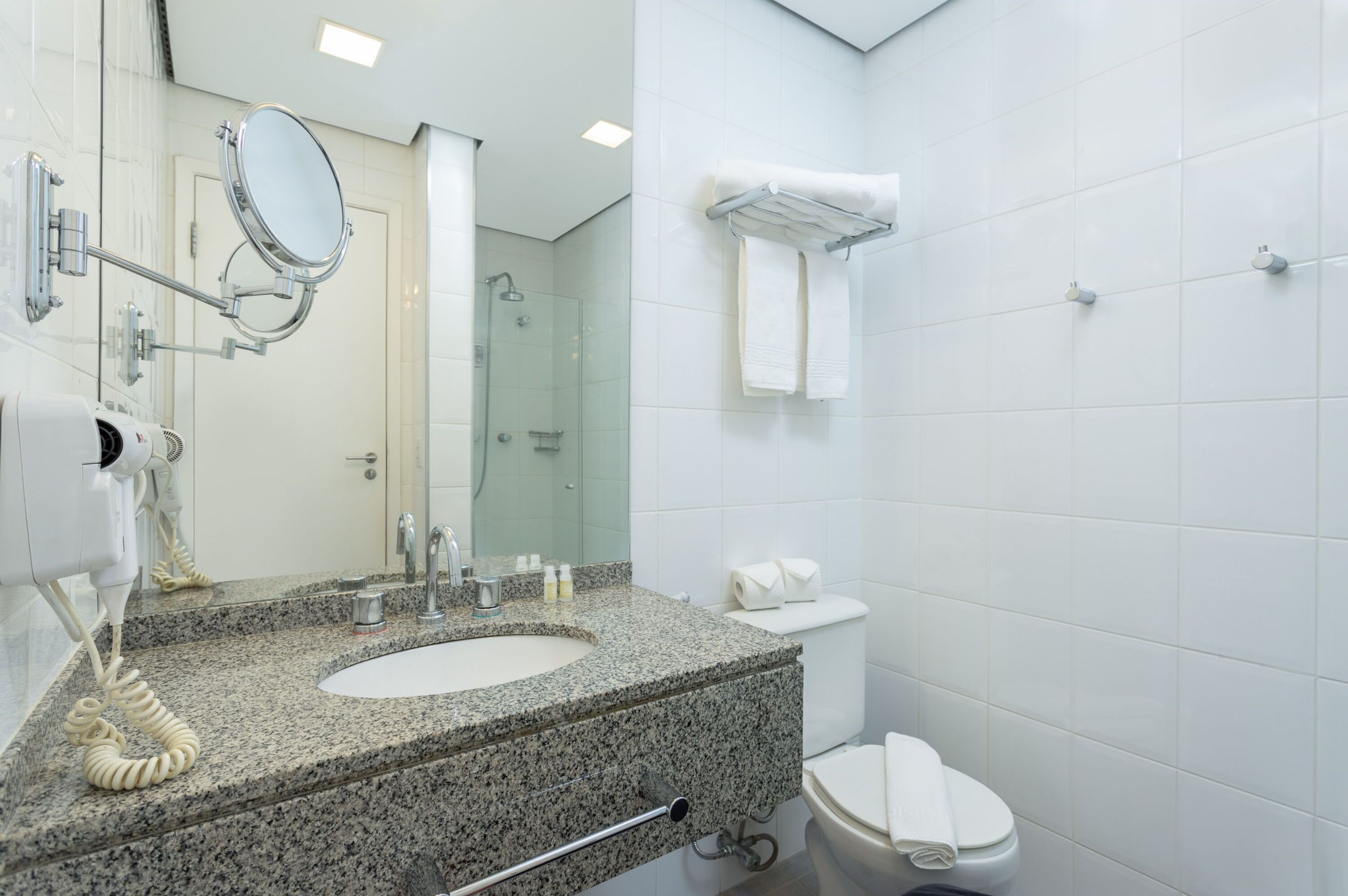 Une salle de bain moderne avec un lavabo en granit, un miroir à main, un porte-serviettes et des toilettes.