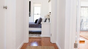 A hallway with wooden flooring and white walls, leading to a bedroom with a bed and a nightstand. - Amazing, secluded twenty-five acre property - yet close to everything you need! (Lovedale)