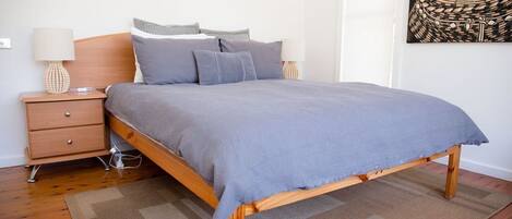 Una camera da letto con una struttura letto in legno, una coperta grigia e due comodini con lampade.