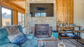 Un salon chaleureux avec une cheminée en pierre, des murs en bois et un canapé confortable.