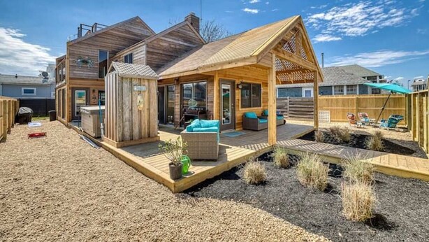 Une maison moderne en bois dotée d’un patio couvert et d’un espace salon extérieur.