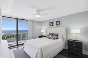Ein modernes Schlafzimmer mit einem großen Bett, einem Balkon mit Aussicht und einem Deckenventilator.