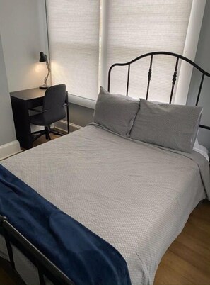 Cozy retreat with a single bed, black metal headboard, and a compact desk area.