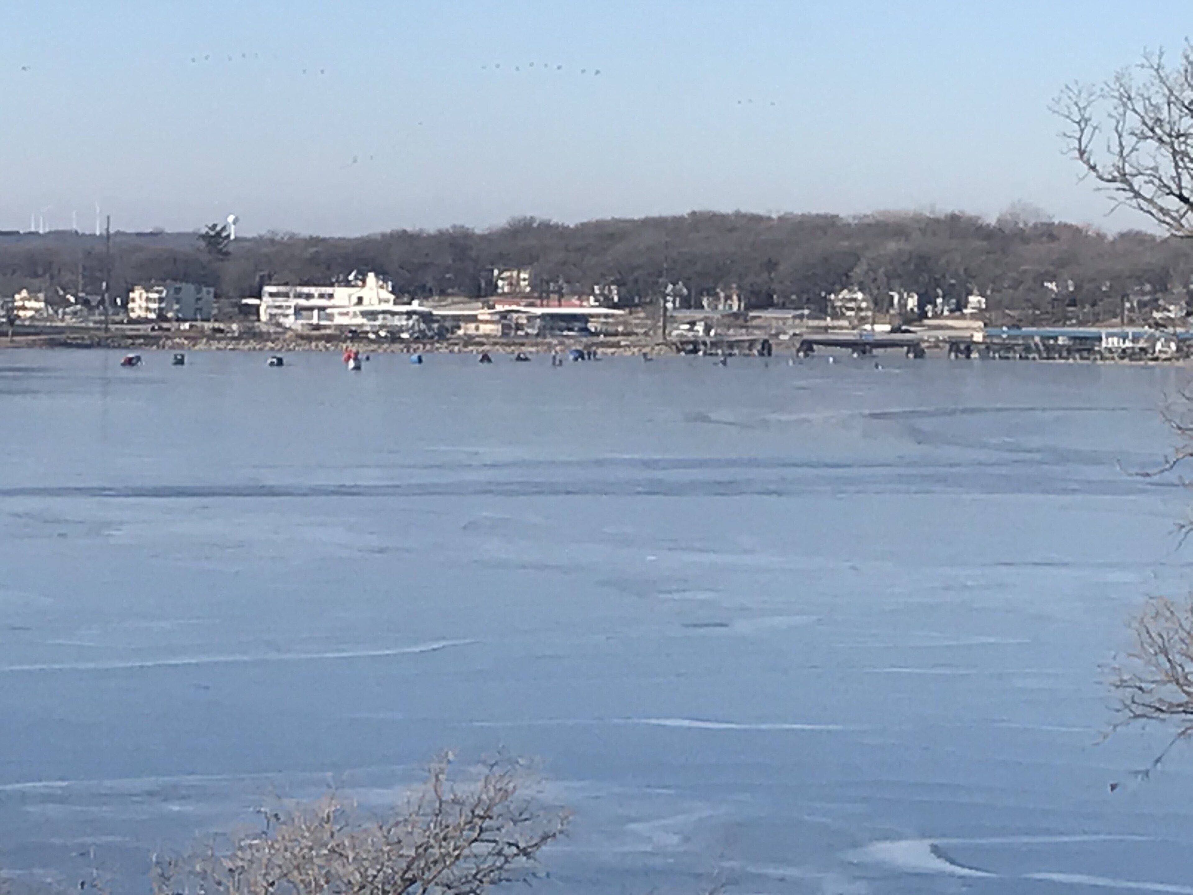 A frozen body of water with buildings and trees in the background.