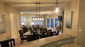 Una cocina con encimera de granito, zona de comedor con mesa y sillas, y chimenea de piedra.
