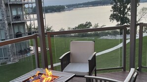 Una terraza con un brasero, dos sillas y vistas a un río y edificios al fondo.