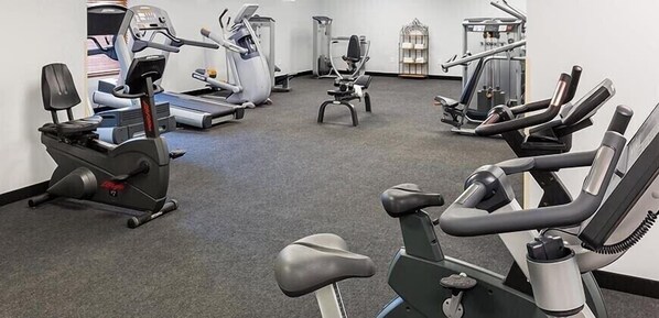 Ein Fitnessraum mit Laufbändern, Crosstrainern und Gewichten.