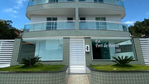 Um edifício de vários andares com escadaria central, varandas de vidro e uma placa com a inscrição 