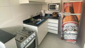 Uma cozinha compacta com fogão a gás, micro-ondas e geladeira.