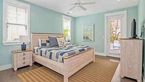 Ein Schlafzimmer mit Bett, Nachttisch, Kommode und Deckenventilator.