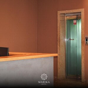 Een receptiebalie met een groene deuren naar de lift, waarop 'Marika Hotel' staat.