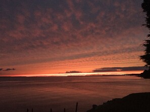 Un atardecer sobre una superficie acuática tranquila con una costa distante.