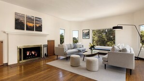 A modern living room with a fireplace, a sofa set, a coffee table, and large windows offering a view of the outdoors. - Stunning, Private Home With Pool, Hot Tub, and Mountain Views! (Santa Barbara)