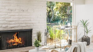 Un salon moderne doté d’une cheminée, de sièges confortables et offrant une vue sur un jardin.