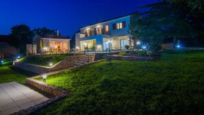 A modern two-story house with a stone facade, a well-lit entrance, and a landscaped front yard. - Villa Cedar with large swimming pool and summer kitchen (Gostinjac (Krk))