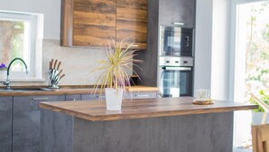 A modern kitchen with wooden cabinets, a central island, and a built-in oven. - Villa Cedar with large swimming pool and summer kitchen (Gostinjac (Krk))