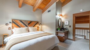 A bedroom with a large bed, wooden headboard, bedside table, and a mirror.