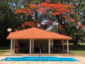 Un espacio exterior cubierto con piscina, una parrilla y una mesa de comedor.
