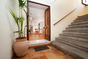 Eine Treppe führt zu einem Essbereich, neben dem Eingang steht ein Blumentopf.