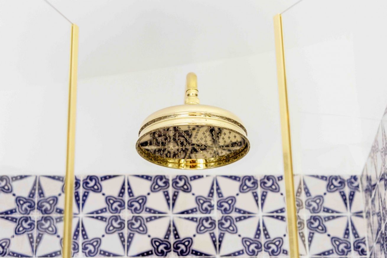 A ceiling-mounted light fixture with a gold-colored base and a patterned glass cover.