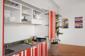 A kitchen with white cabinets, a red-striped door, a sink, and a potted plant. - Deluxe Home in Sorrento Old Town with Balconies (Sorrento)