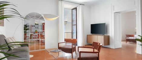 Amplia sala de estar con sofá, sillas, televisor y comedor.