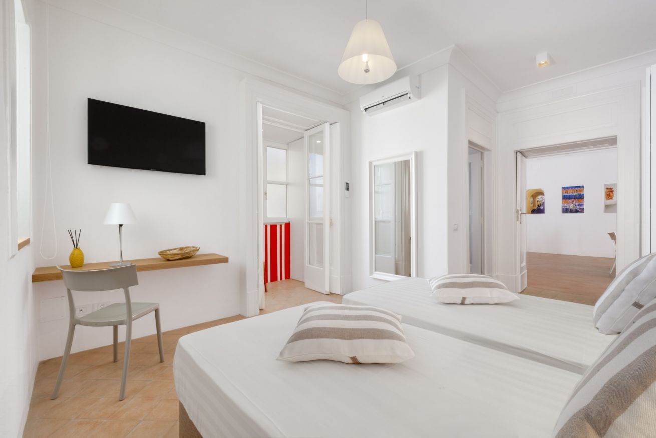 Ein modernes Hotelzimmer mit einem großen Bett, einem Schreibtisch mit Lampe und einem Fernseher an der Wand.