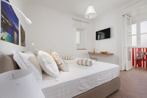A modern bedroom with a large bed, a flat-screen TV, and a window with a view of the cityscape. - Deluxe Home in Sorrento Old Town with Balconies (Sorrento)