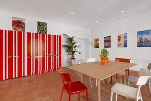 Un comedor con una mesa y sillas de madera, un separador a rayas rojas y blancas, y varias obras de arte en las paredes.