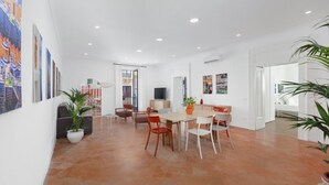 A spacious dining area with a large table and chairs, a television, and a potted plant. - Deluxe Home in Sorrento Old Town with Balconies (Sorrento)