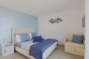 A bedroom with a bed, a nightstand, a chair, and a decorative wall piece.