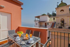 Un balcón con una mesa preparada para el desayuno, con vistas a la costa.