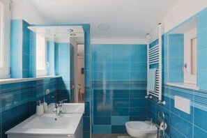 Un baño con azulejos azules, un lavabo, un inodoro y un espejo.