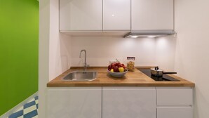 A kitchen with white cabinets, a stainless steel sink, a wooden countertop, and a bowl of fruit. - Luxury&Romantic Apartment with Balcony in Sorrento (Sorrento)