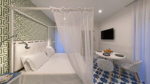 Ein Schlafzimmer mit einem Bett, einem Nachttisch, einem Fernseher und einem Essbereich mit Stühlen und einem Tisch.