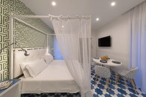 Ein Schlafzimmer mit einem Bett, einem Nachttisch, einem Fernseher und einem Essbereich mit Stühlen und einem Tisch.
