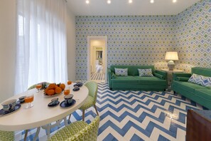 A modern living room with a green sofa set, a dining table with orange fruits, and patterned walls. - Design Holiday Home in Sorrento city center (Sorrento)