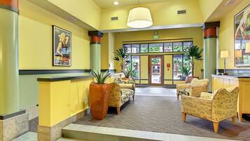 A lobby with a reception desk, seating area, and a staircase leading to an upper floor.
