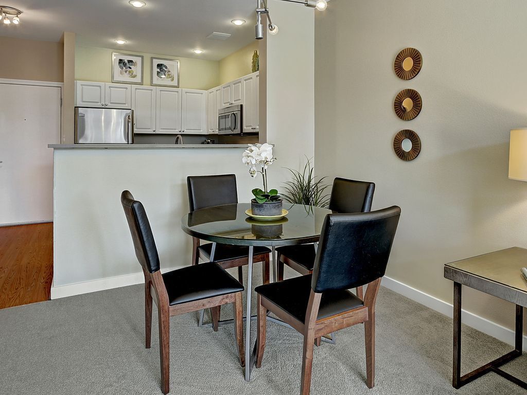 A dining area with a round table, four chairs, and a small potted plant.