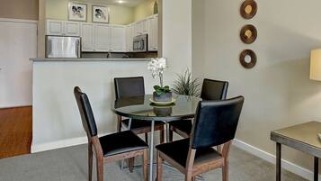 A dining area with a round table, four chairs, and a small potted plant.