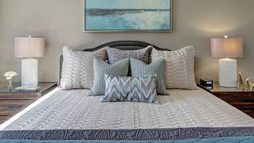 A neatly made bed with a quilted bedspread, multiple pillows, and two bedside lamps.