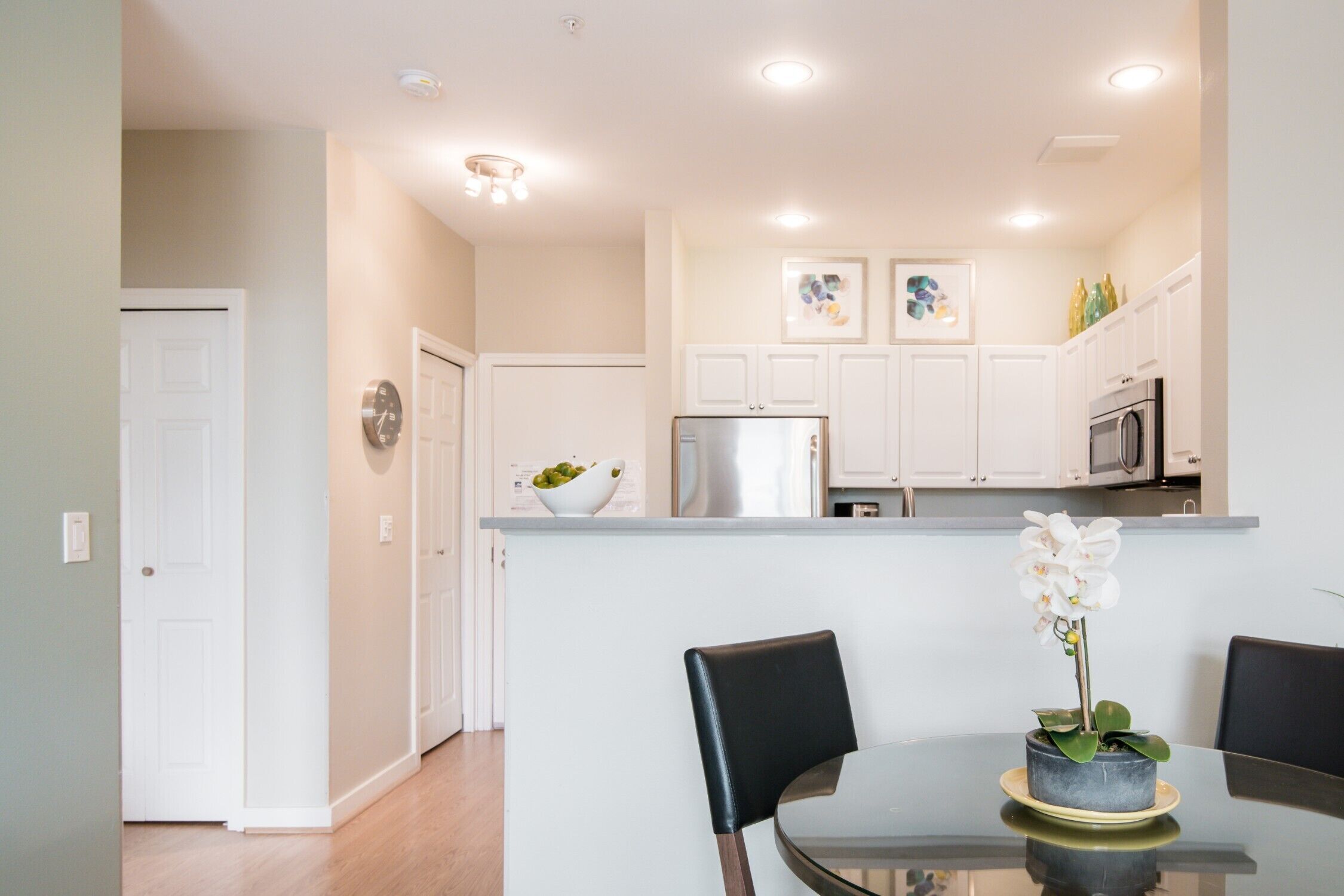 A modern kitchen with white cabinets, a stainless steel refrigerator, and a microwave.