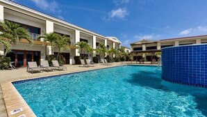 A hotel pool area with lounge chairs and palm trees.